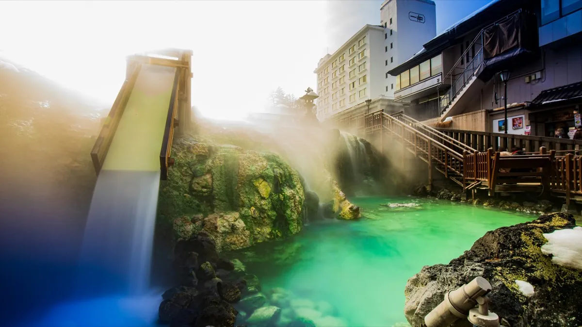 Groen thermaalwater en houten afkoelhelling van de Yubatake in Kusatsu
